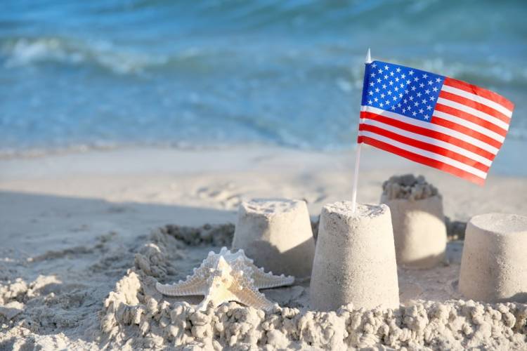 Sand castle with American flag on beach.