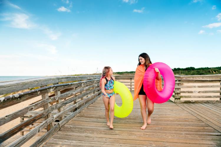 two young girls with inner tubes walking back from beach