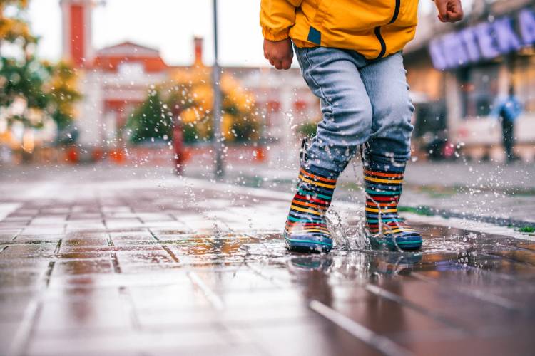 little kid jumping in a puddle on a rainy day