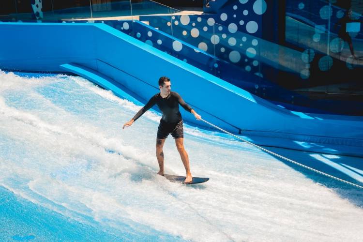 Young man surfing on a wave simulator at a water amusement park.